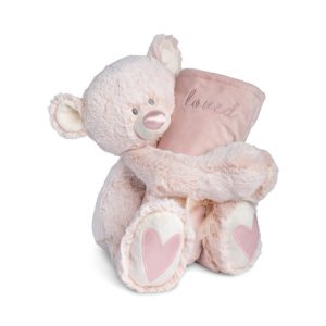 A light pink teddy bear with a pink nose and pink hearts on its paws holding a rolled soft pink blanket that says "loved".